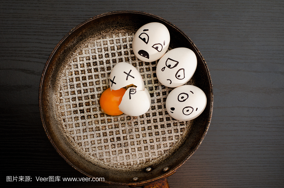 三个鸡蛋涂上情绪,破碎的蛋在锅中心,黑色的桌