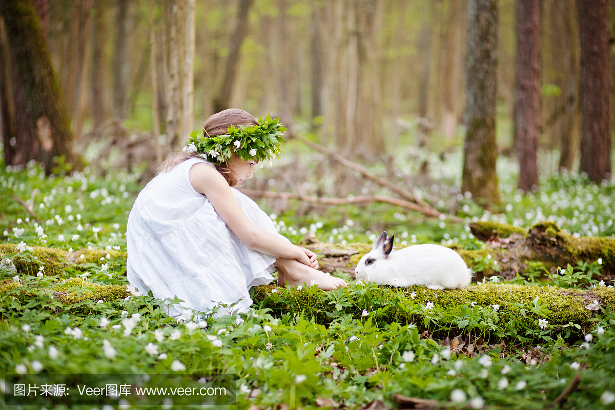 漂亮的小女孩,在春天的木头与白色兔子plaing白
