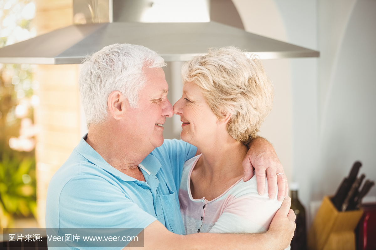 高级情侣在厨房接触鼻子时拥抱