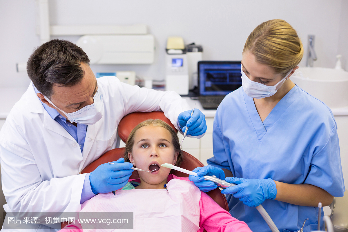 Dentist and nurse examining a young patient wi