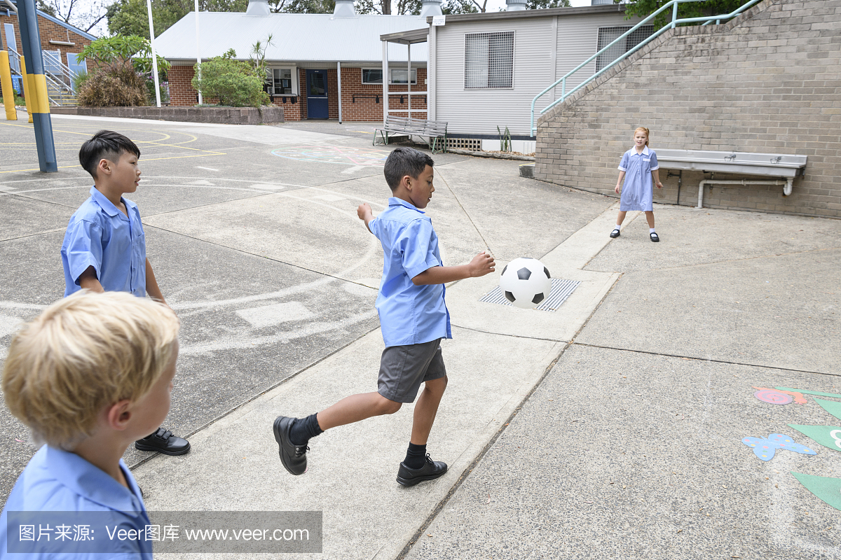 四个多种族的孩子在学校操场上踢足球