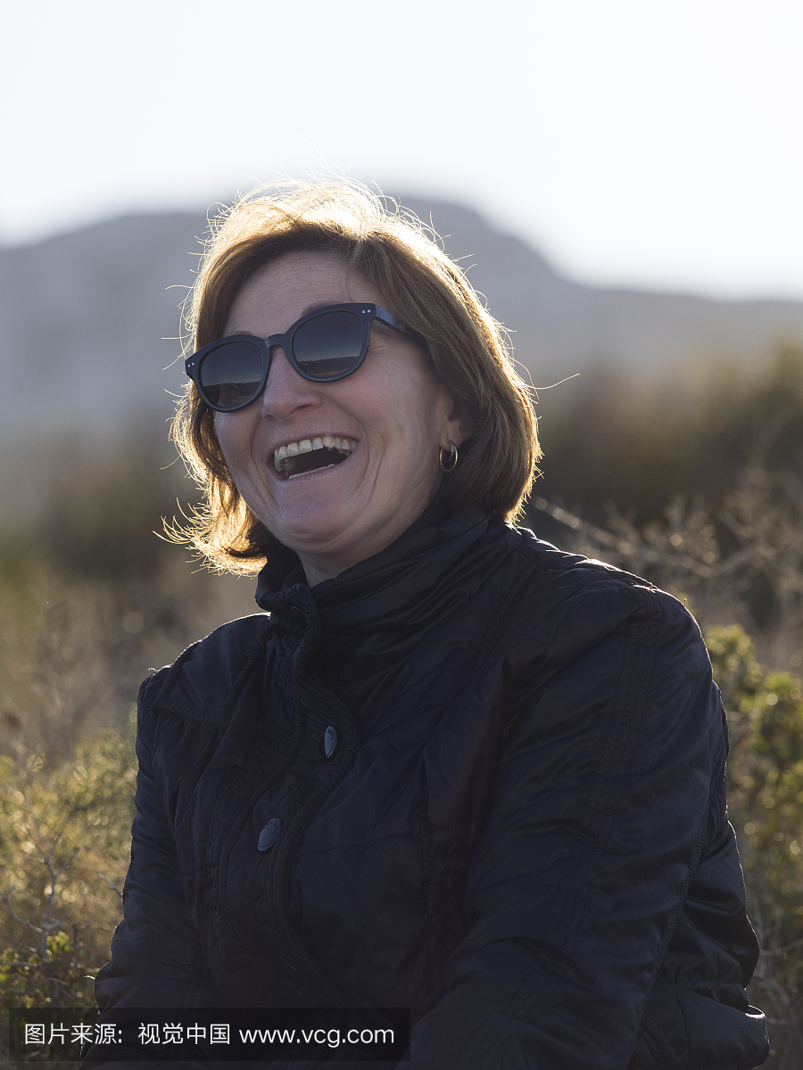 中年的女人与太阳镜微笑,在性质