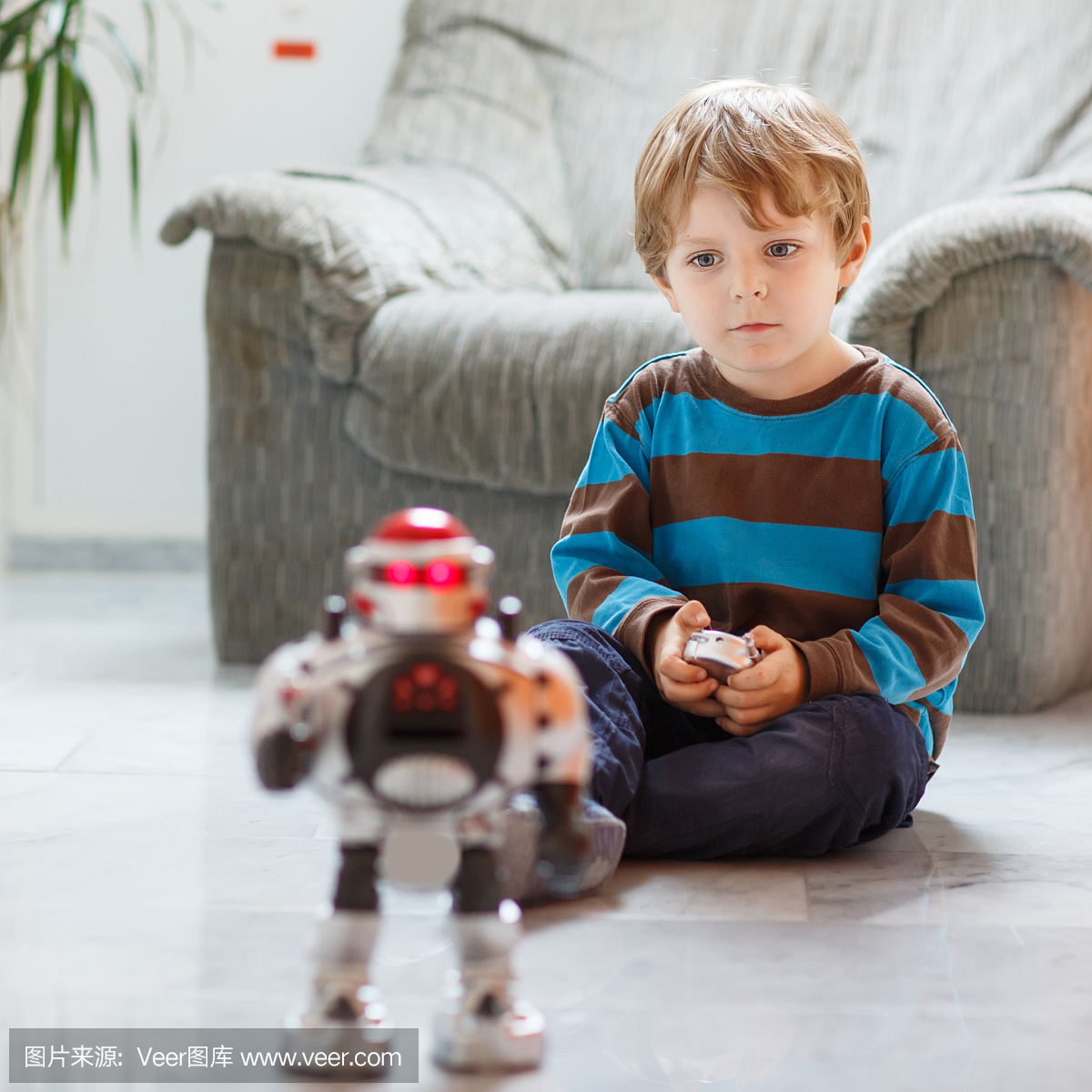 在家里,室内玩机器人玩具的小金发男孩。