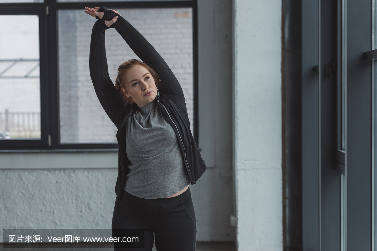 在舒展胳膊的健身房的肥胖女孩