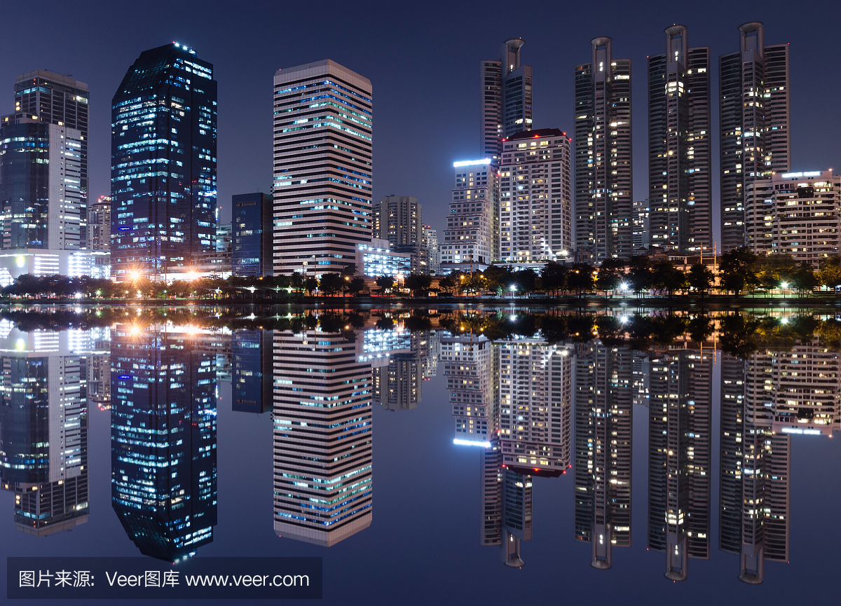 从现代建筑光在晚上城市与天际线对称水镜面反射明亮。夜晚的城市景观概念。