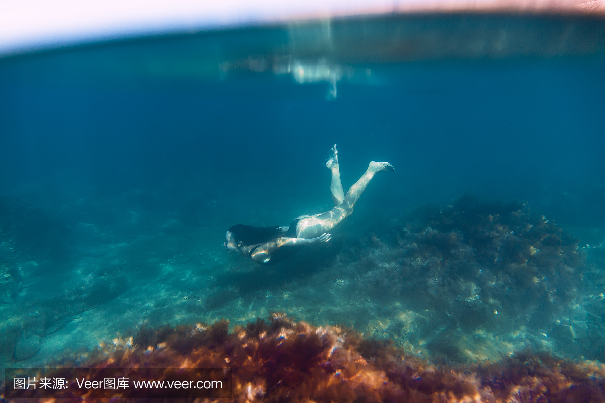 活跃的年轻女子在比基尼游泳在海洋中,水下潜