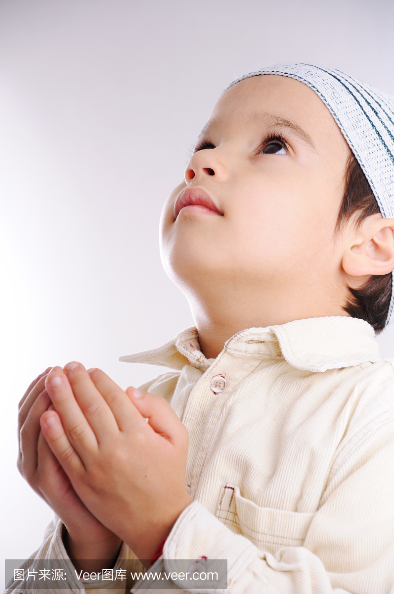 穆斯林小可爱的小孩,戴上帽子,同时祈祷安拉
