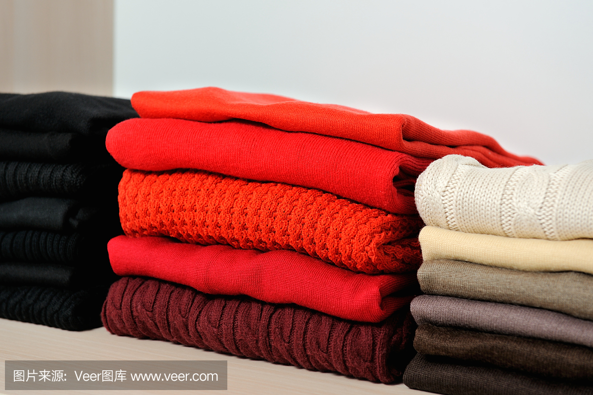 堆栈的舒适多彩针织毛衣在衣柜里。概念保暖的