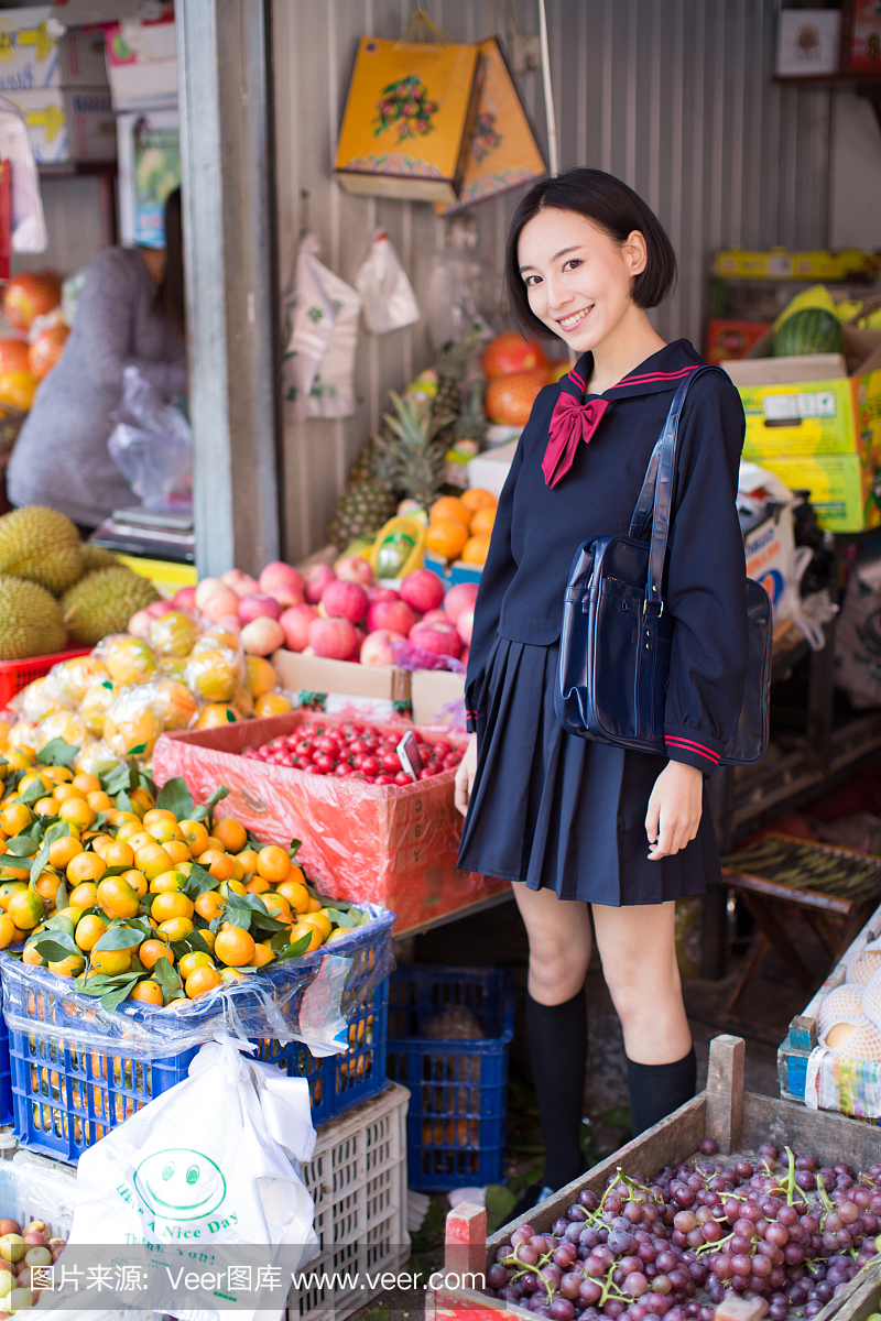 美丽的中国女学生在市场上买水果和蔬菜