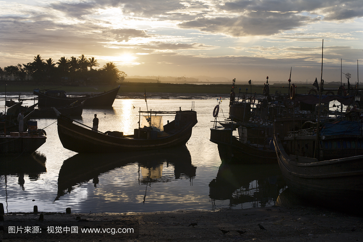钓鱼的剪影在日出停泊的小船在批发鱼市场在巴