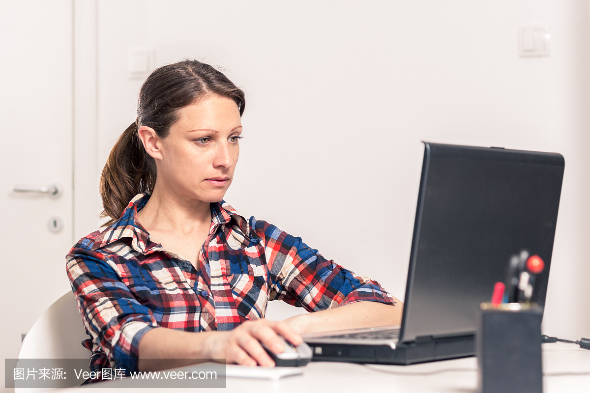 妇女在笔记本电脑上工作的照片