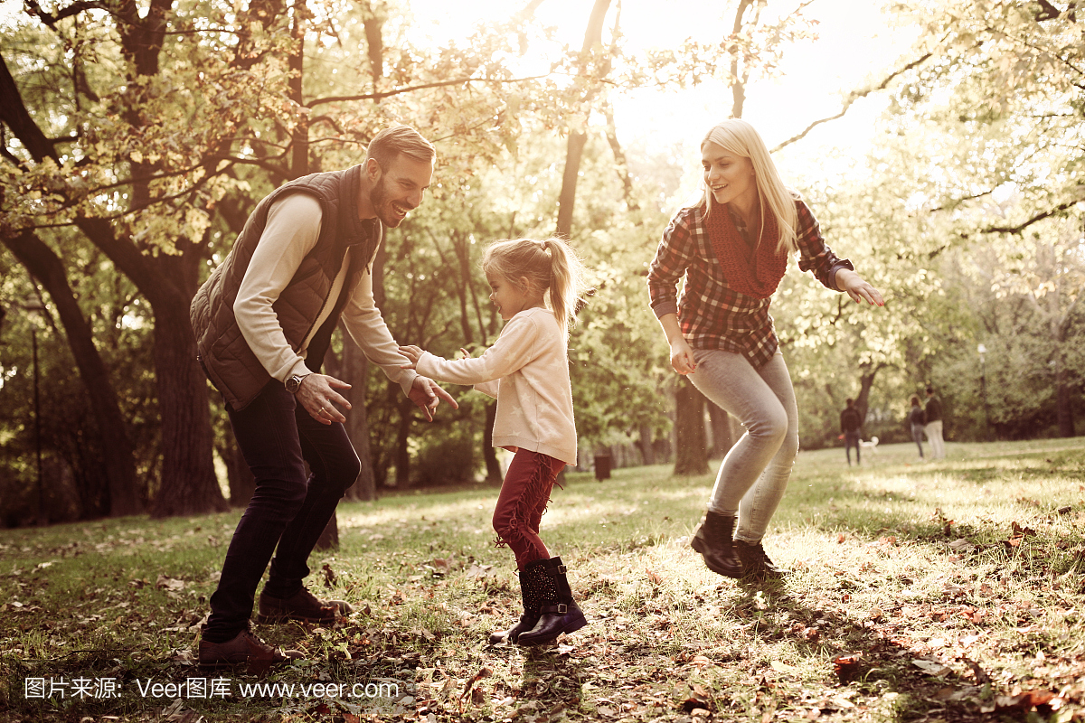 快乐的父母与他们的小女儿在公园玩。