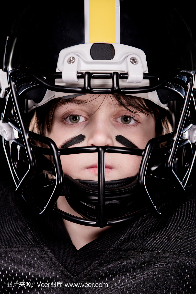 男孩美式橄榄球运动员在看着相机的头盔的特写