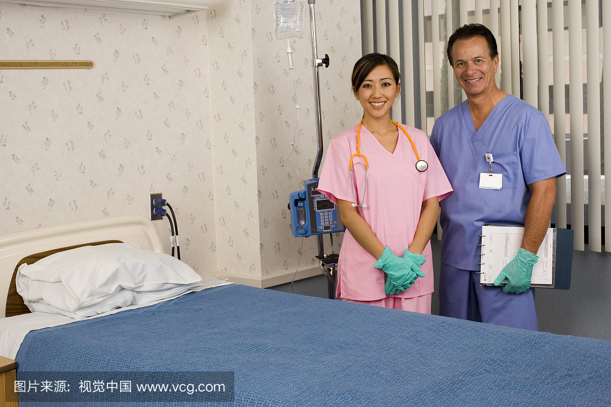 医生和护士在手术磨砂和手套站在医院的床边,