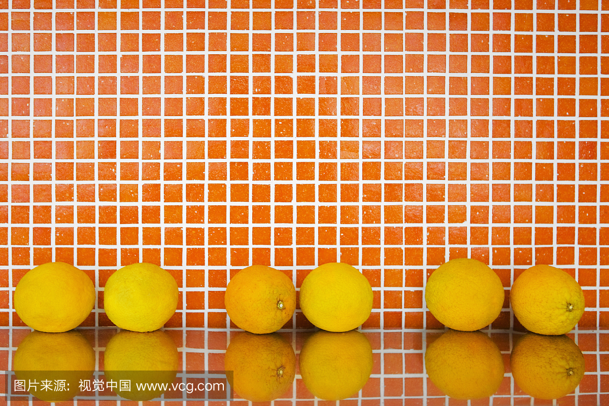 六个橙子对着橙色的墙壁。
