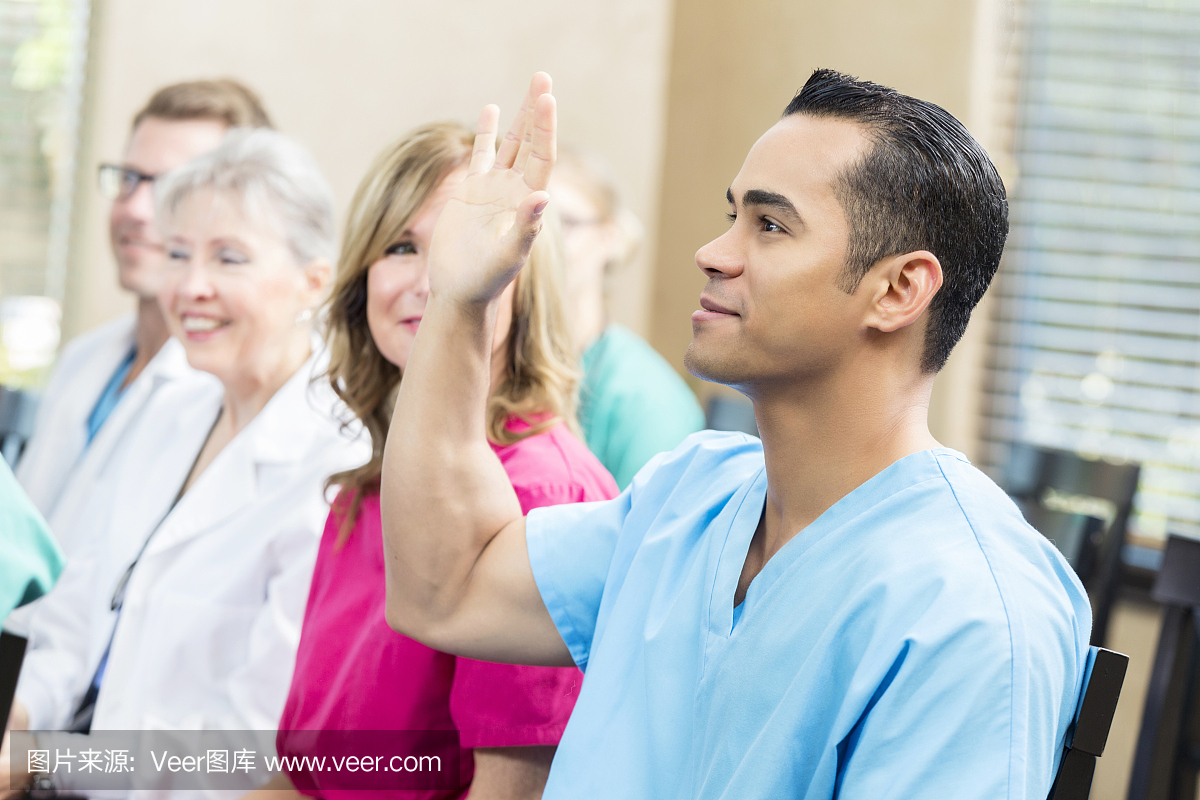 年轻的西班牙医疗专业人员在会议期间举手