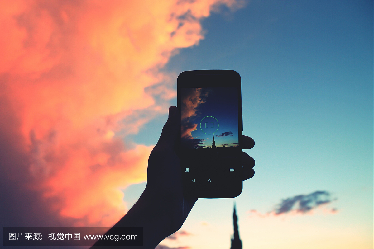 在黄昏时期剪影人物手机反对天空的裁剪图像