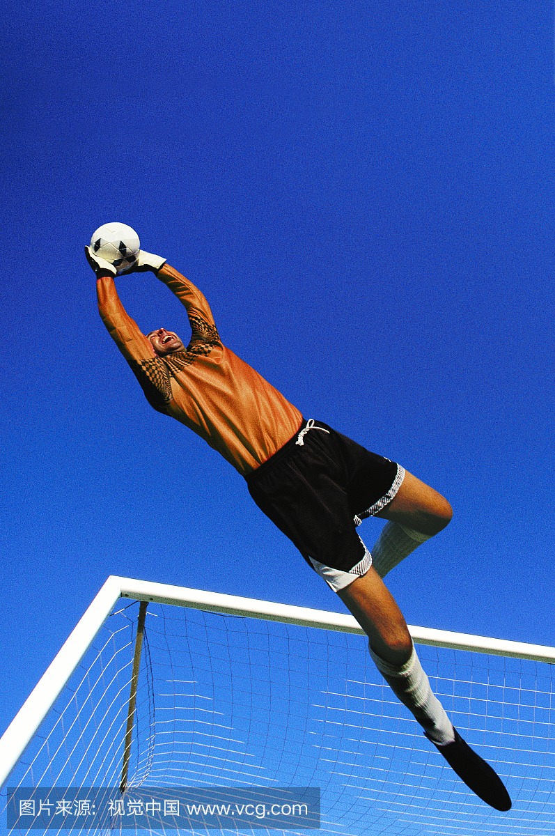 足球守门员捕捉球在半空中,目标在背景中
