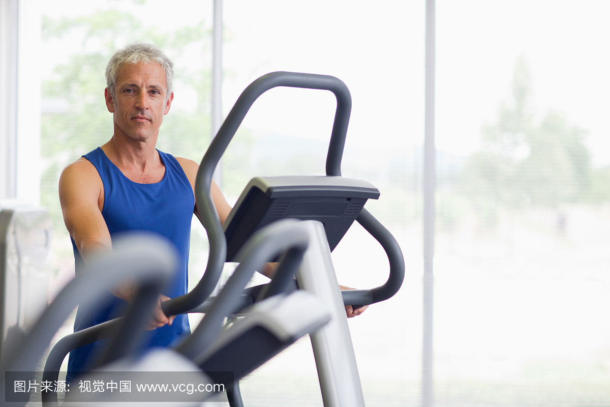 在健身房的椭圆机上的微笑的人的肖像