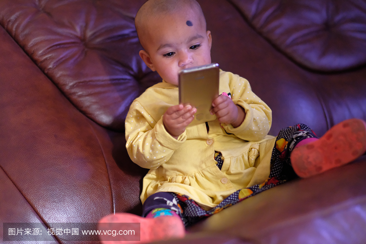 一岁的宝宝玩坐在沙发上的手机
