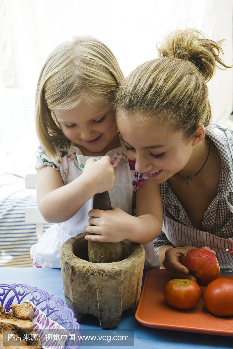 Sisters using mortar and pestle together