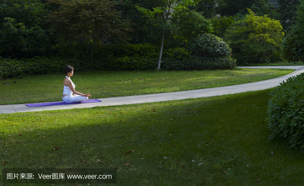 在瑜伽垫的女人放松在公园里。
