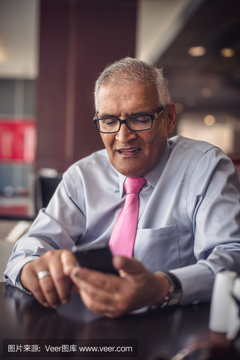 英俊的印度商人使用智能手机
