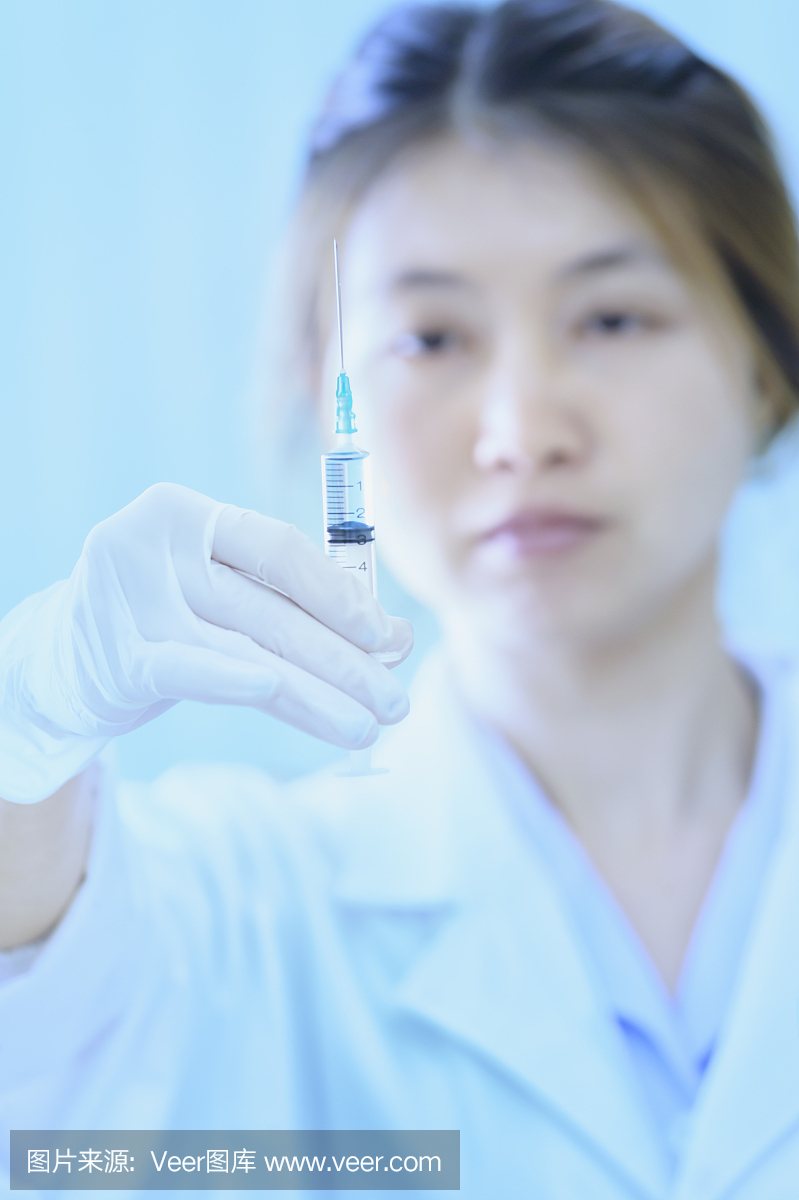 亚洲年轻医生女人与注射器在医院
