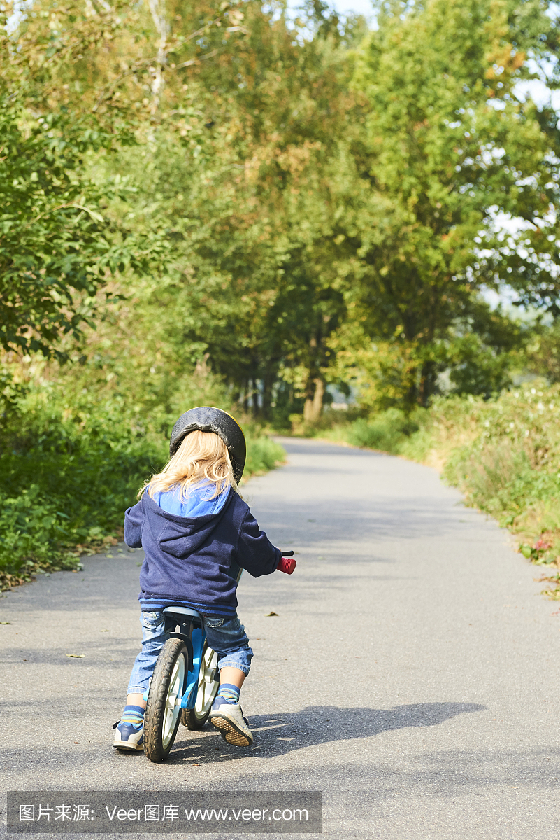 儿童骑行平衡自行车。孩子骑自行车在晴朗的公