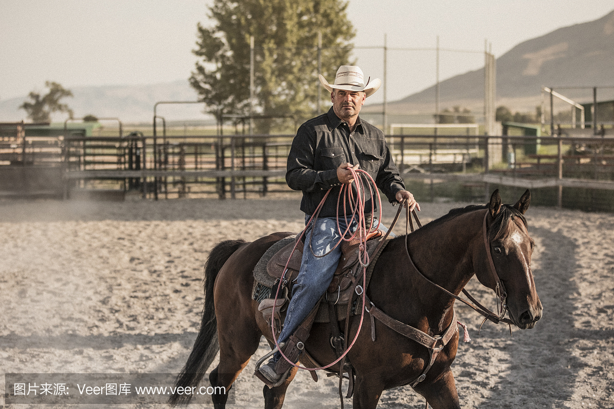 他的马上有一个牛仔骑在竞技场场地上。