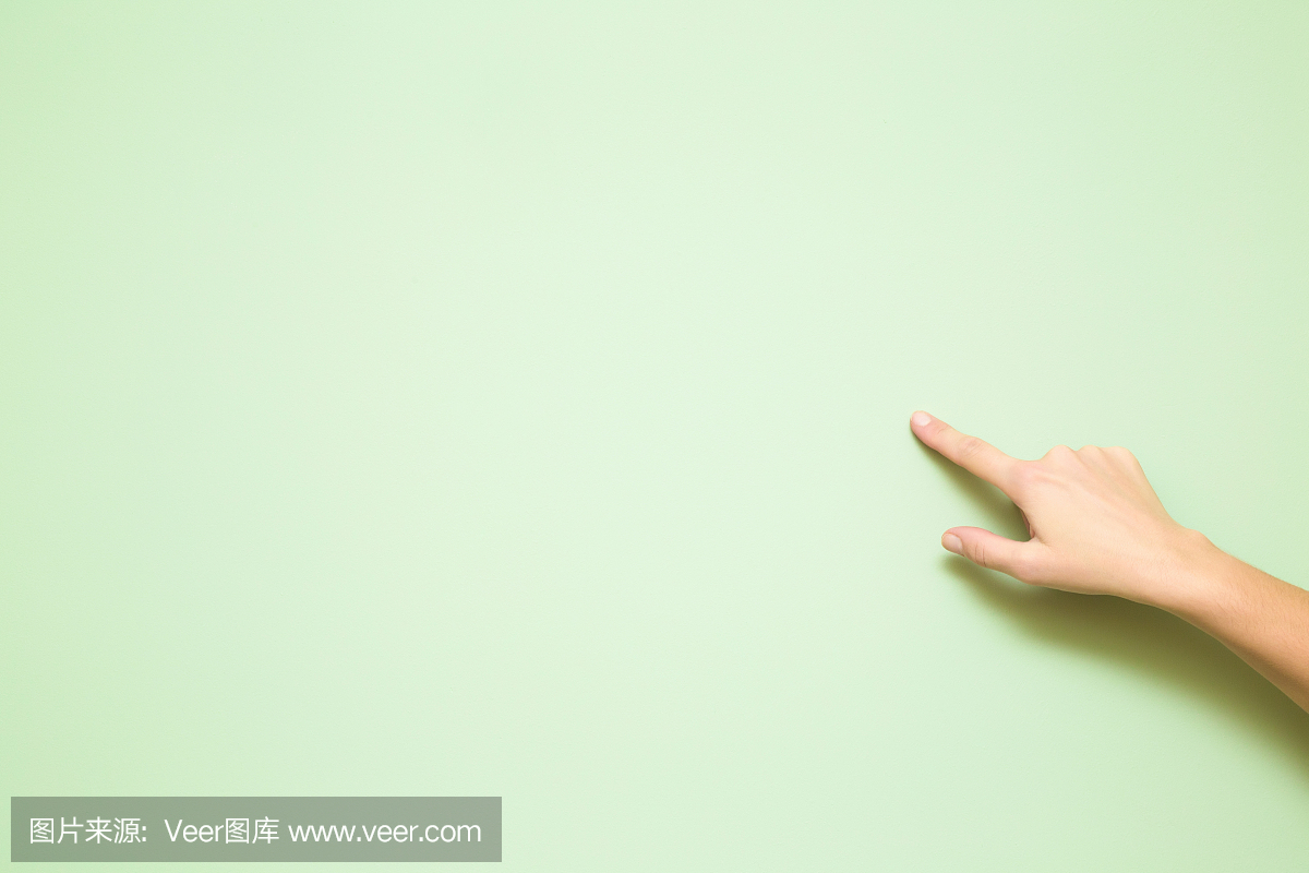 指向在浅绿色的墙壁上的女人的手。嘲笑特殊优